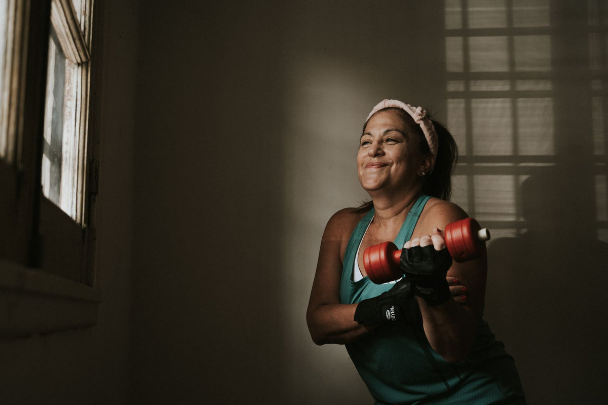 A middle-aged woman exercising with dumbbells at home